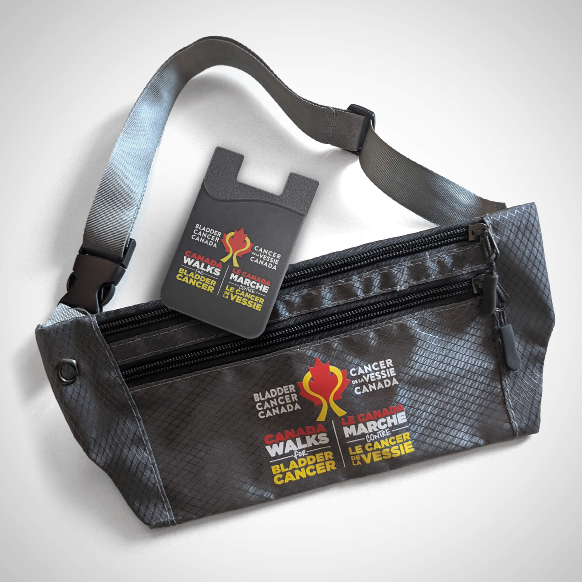 Dark Gray fanny pack and dark grey peel-and-stick phone wallet. Both have the Bladder Cancer Canada bilingual logo printed on them.